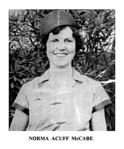 A woman in a hat standing next to trees.