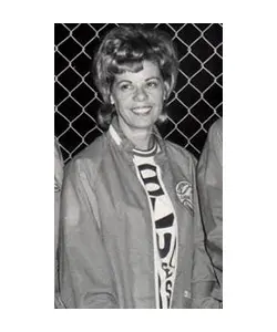 A woman in a jacket and t-shirt standing next to a fence.