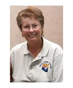 A woman with short hair and glasses wearing a white shirt.