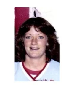 A woman with long hair and wearing a baseball uniform.