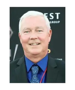 A man with white hair and blue shirt.