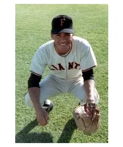 A baseball player kneeling on the field with his mitt.