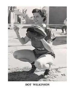 A woman squatting on the ground holding a frisbee.