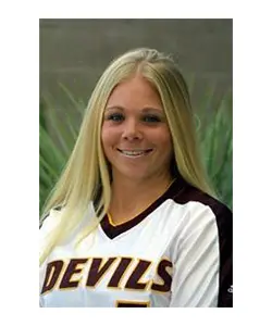 A woman in a baseball uniform poses for the camera.