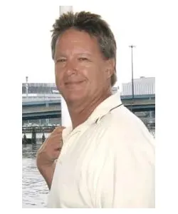 A man in white shirt standing next to water.