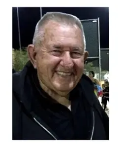 A man with gray hair and glasses smiling.