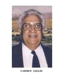 A man with white hair and glasses wearing a suit.