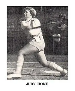 A woman swinging a baseball bat on top of a field.