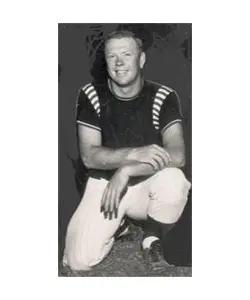 A man sitting on the ground in his baseball uniform.