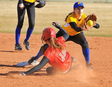 A softball player sliding into the base while another player catches the ball.